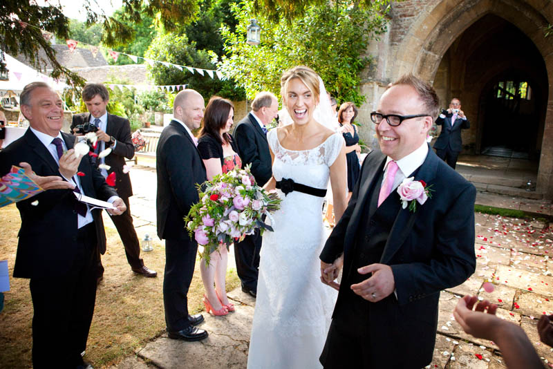 A bride and groom walk outside just after getting married at Sheldon Manor wedding venue in Chippenham