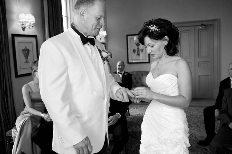 Black and white photo of the bride putting the ring on her husband's finger at The Mount Somerset wedding venue