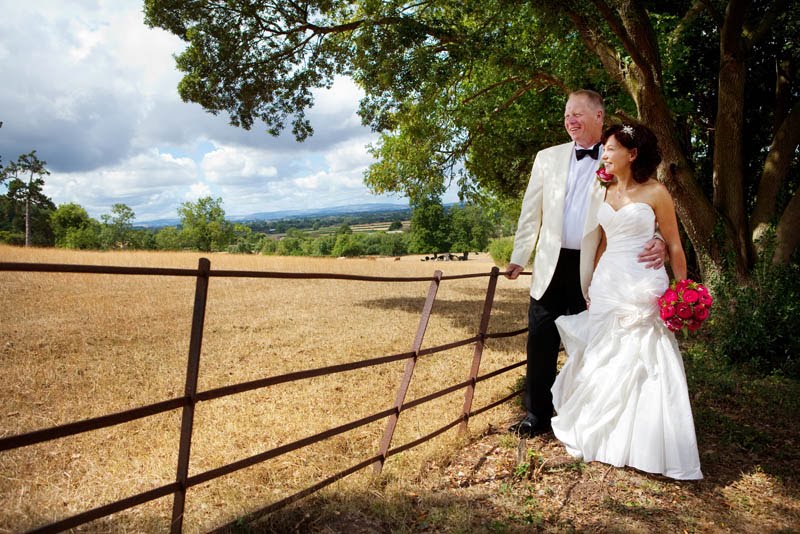 A bride and groom look out of the fields on a summer day at The Mount Somerset wedding venue