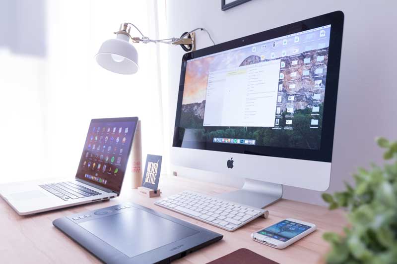 Modern Apple laptop and iMac computer on a desk.