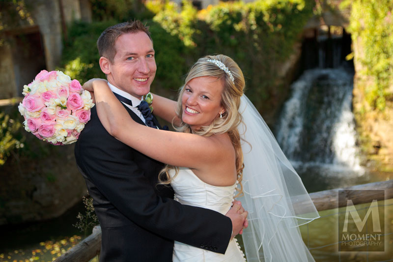 A bride holding her arms around her husband in the Gardens of Gants Mill in Bruton Somerset