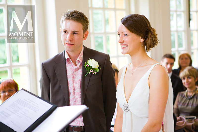 A bride and groom listening to the registrar during a wedding ceremony in the Orangery at Hestercombe Gardens in Cheddon Fitzpaine
