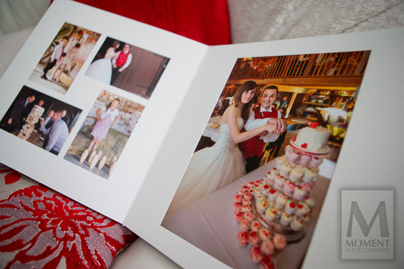 An open page of a large wedding album showing a photo of the bride and groom cutting their wedding cake