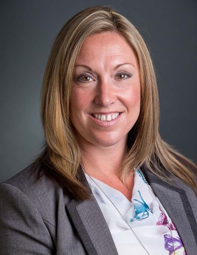 Staff business headshot of a blonde woman with a grey jacket and white top