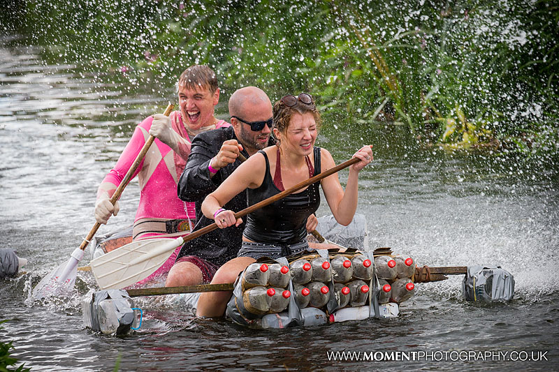 Three adults showered in water from a big hose whilst fancy dress rafting at The Lowland Games 2016