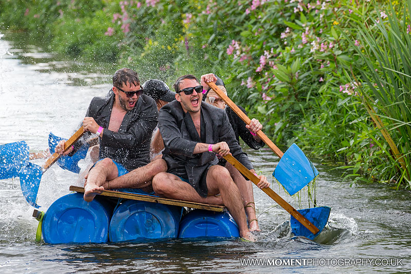 Men in suits and sunglasses showered in water from a big hose whilst fancy dress rafting at The Lowland Games 2016